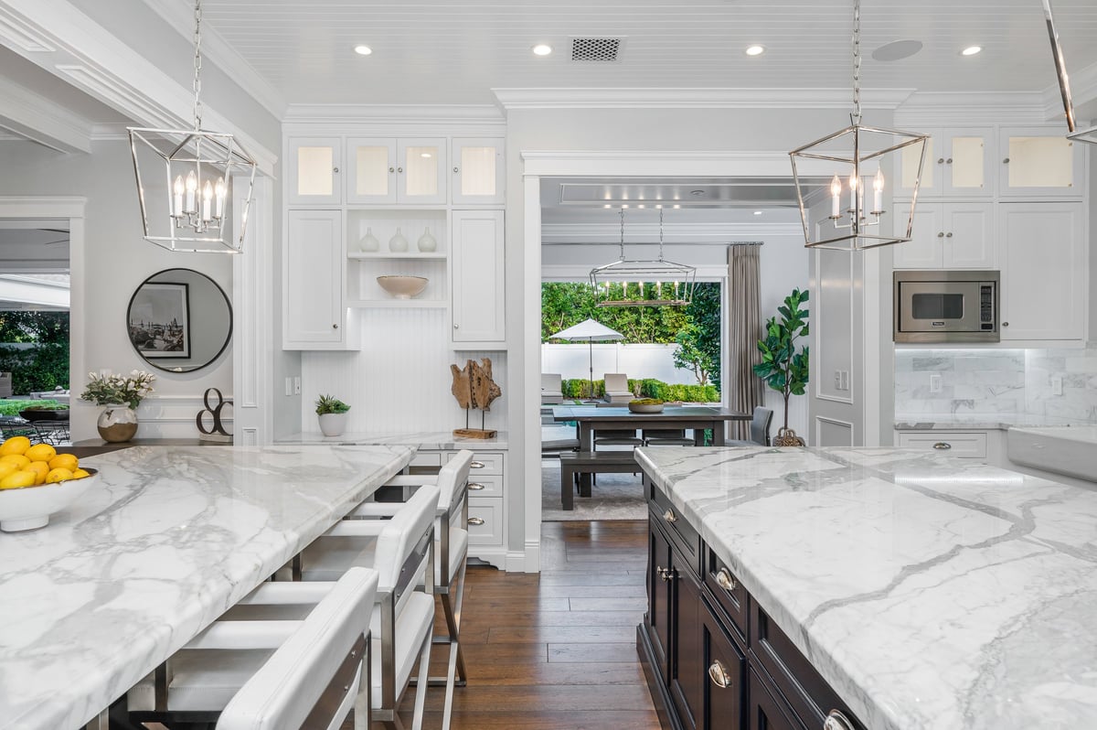 A marble kitchen with a white island, and chairs in a new construction home
