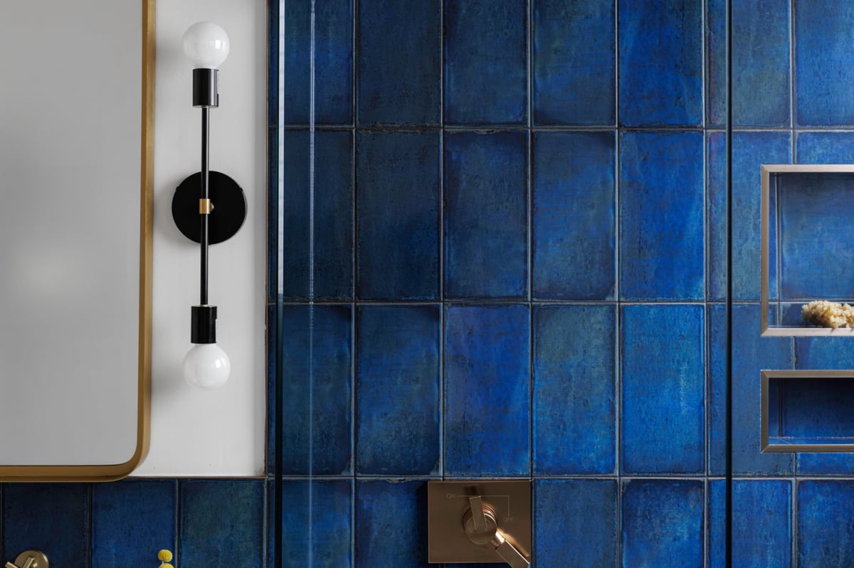 A stylish bathroom showcasing deep blue tiles and a modern black lighting fixture