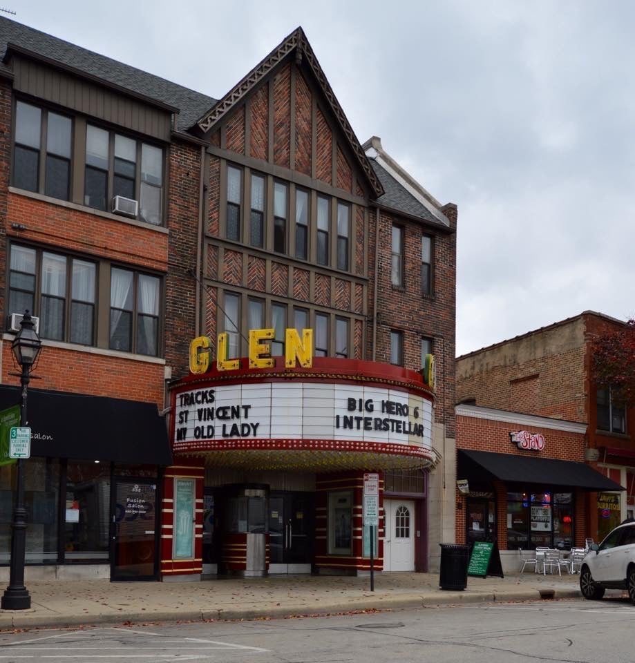 Historic Glen movie theater with brick facade and marquee displaying showtimes in a downtown streetscape