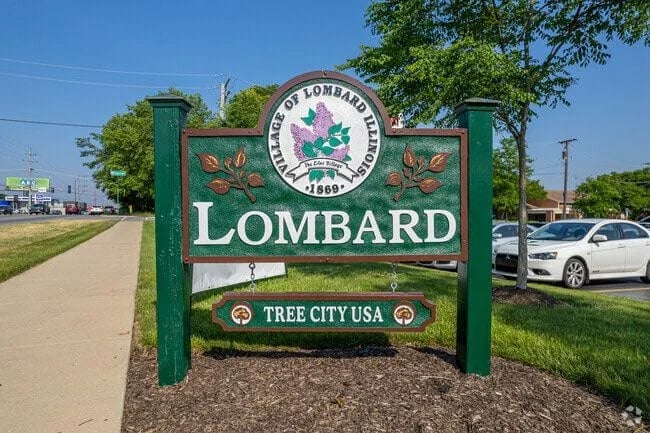 Green Lombard city welcome sign with Tree City USA designation under clear blue sky along roadside